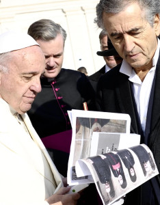 Bernard-Henri Lévy shows images of the four monks to Pope Francis.