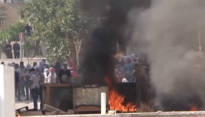 Palestinian are seen standing nearby a fire. PA President Mahmoud Abbas has accused Jews of “defiling Al-Aqsa mosque with their filthy feet,” praised the “holy blood” of the “martyred” killers and condemned Israel for “murdering” the terrorists. Photo: Wikimedia Commons.