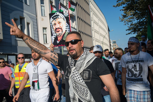 An anti-Semitic protester in Berlin with a pro-Nazi tattoo on his arm. Photo: Wikimedia Commons.